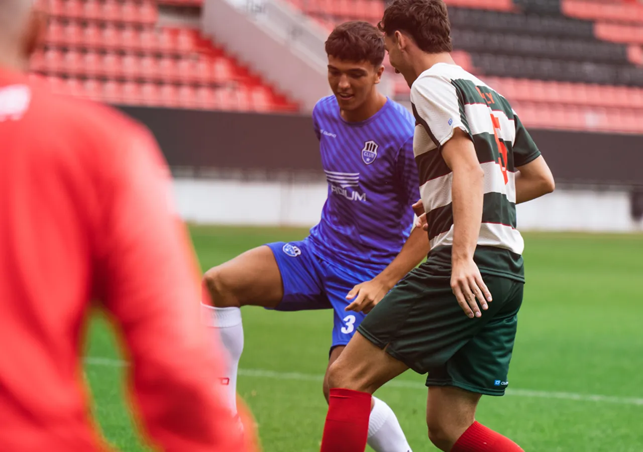 Two soccer players in action on the field, one wearing a blue jersey and the other in a striped jersey.