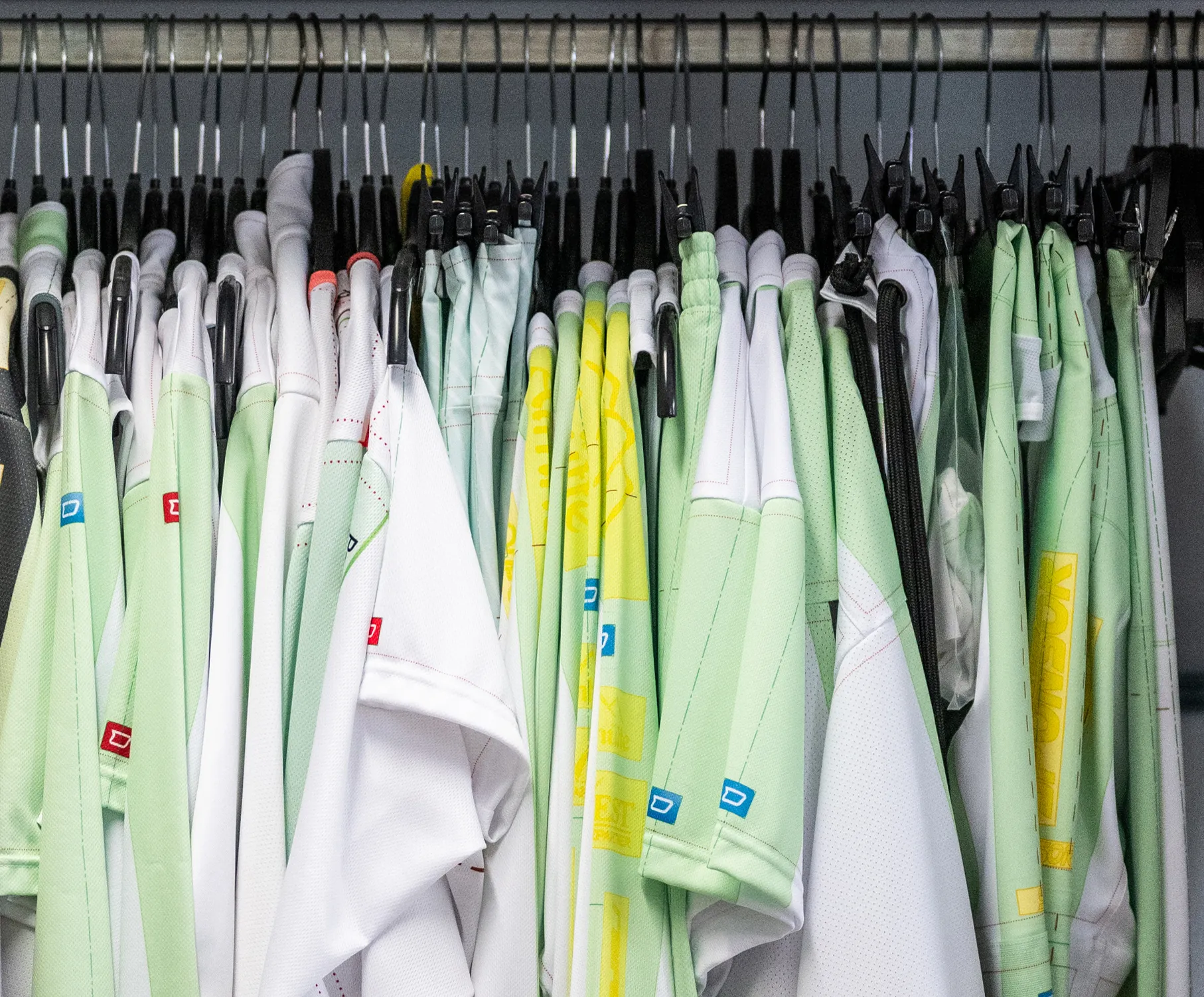 A selection of customized sportswear in various colors hanging on hangers.